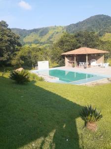a swimming pool with a gazebo in a yard at Chalé Caminho Real in Itamonte