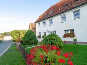 a white house with red flowers in a yard at Ferienwohnung Hertel in Mistelgau