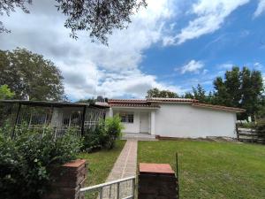 a white house with a fence in a yard at Casa hasta 10 personas. in Villa Rumipal