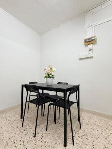 a black table with chairs and a vase with flowers at Kuantan Tiny Homestay in Kuantan
