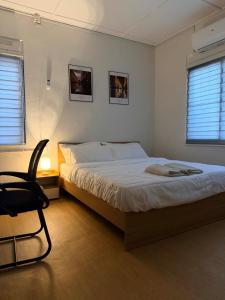 a bedroom with a bed and a chair and two windows at Kuantan Tiny Homestay in Kuantan