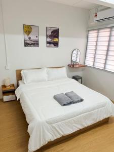 a bedroom with a large white bed with two towels on it at Kuantan Tiny Homestay in Kuantan +9 photos