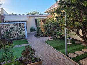 a garden with a brick walkway in front of a house at Cowes Cottage in Fish Hoek