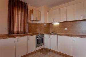 a kitchen with white cabinets and a sink at Hotel Vemara Club in Byala