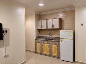 a kitchen with a white refrigerator and wooden cabinets at شركة العييري للشقق المخدومة شركة شخص واحد الاحساء 2 in Al Ahsa