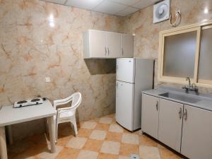 a kitchen with a white refrigerator and a table and a sink at شركة العييري للشقق المخدومة شركة شخص واحد الاحساء 2 in Al Ahsa +23 photos