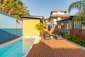 a deck with chairs and a swimming pool and a building at SPA-AC-BBQ-Casa Container-Cozinha Completa in Florianópolis
