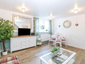a living room with a tv and a table at Hideaway Cottage in Hunstanton