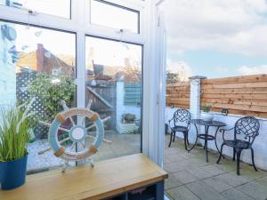 a patio with a table and chairs and a window at Hideaway Cottage in Hunstanton