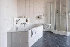 a white bathroom with a tub and a toilet at Hotel INGREDI in Bree +19 photos