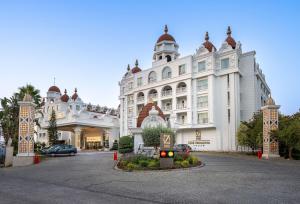 a large white building with a parking lot in front of it at Oz Hotels Side Premium in Side