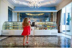 a little girl in a red dress standing in front of a store at Oz Hotels Side Premium in Side +291 photos