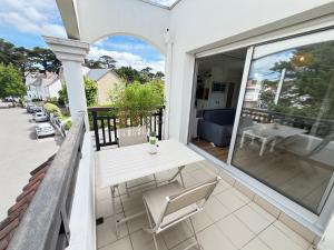 a patio with a white table and chairs on a balcony at Le Cocon Baulois in La Baule +4 photos