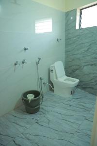 a bathroom with a toilet and a bucket in it at Vetri Residency in Agastīswaram