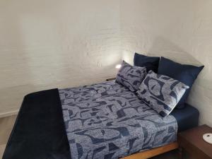 a bedroom with a bed with a blue comforter and pillows at Cowes Cottage in Fish Hoek