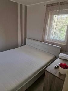 a bedroom with a white bed and a window at Hársfa Jakuzzis Nyaraló Szarvas in Szarvas