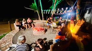 a group of people sitting around a fire pit at night at Flats Theo Peleteiro Praia da concha Flatitacareconcha in Itacaré