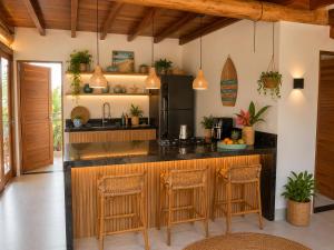 a kitchen with a counter and stools in a room at Flats Theo Peleteiro Praia da concha Flatitacareconcha in Itacaré