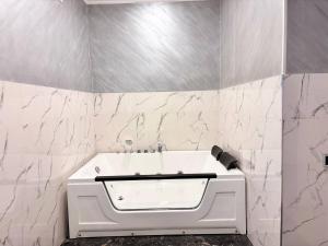 a white tub in a bathroom with marble walls at Regal Hotel in Kapan