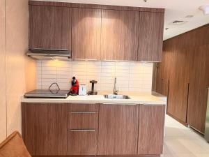 a kitchen with wooden cabinets and a sink at Aesthetic Kings Studio at Uptown Al Zahia Sharjah in Sharjah