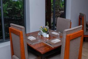 a dining room table with chairs and a table with flowers on it at Winsome Hotel Arusha in Themi