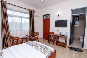 a hotel room with a bed and a desk and a television at Winsome Hotel Arusha in Themi
