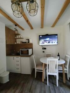 a kitchen with a table and a tv on the wall at Durmitor Forest Retreat in Žabljak