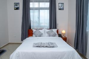a bedroom with a bed with white sheets and a window at Winsome Hotel Arusha in Themi