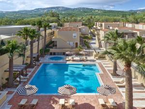 an overhead view of a swimming pool with umbrellas and palm trees at Grecotel Casa Adele in Platanes +55 photos