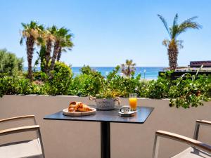 a table with a plate of bread and a glass of orange juice at Venezia Sea Side Suites in Faliraki