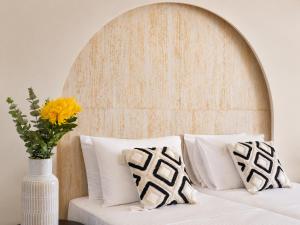 a white bed with a vase with a yellow flower at Venezia Sea Side Suites in Faliraki +2 photos