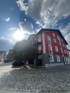 a red and white building with a tree next to it at Eibisch Apartments in Passau
