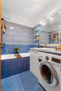 a blue tiled bathroom with a washing machine at Slunný byt v Berouně in Beroun