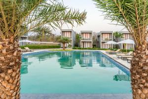 a swimming pool with palm trees in front of a resort at Vanam at Sasan in Sasan Gir +38 photos
