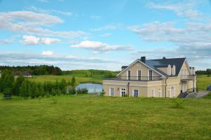 a large house in a field with a lake at Kambarys prie vynuogyno in Pikeliškės
