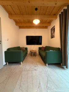 a living room with two green couches and a flat screen tv at Chata ŠENKÁRKA Zuberec in Zuberec