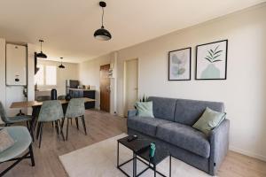 a living room with a couch and a table at Le Traversant - Parking Gratuit in Bourg-lès-Valence