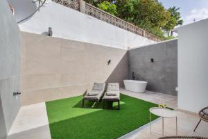 a bathroom with a green floor and two chairs and a tub at Odi Suite&Home in Maspalomas