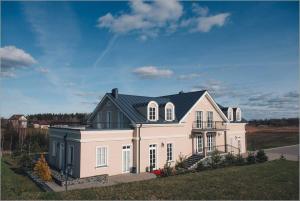 a large white house with a black roof at Kambarys prie vynuogyno in Pikeliškės