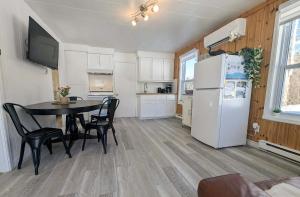 a kitchen and dining room with a table and a refrigerator at Relaxing Chalet Getaway with Spa Fireplace & BBQ in Saint-Tite-des-Caps