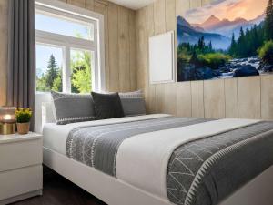 a bedroom with a bed with a painting on the wall at Relaxing Chalet Getaway with Spa Fireplace & BBQ in Saint-Tite-des-Caps