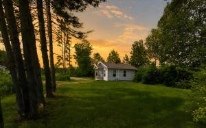 a small white house in the middle of a yard at Relaxing Chalet Getaway with Spa Fireplace & BBQ in Saint-Tite-des-Caps +33 photos