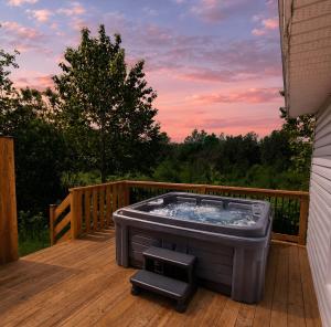 a hot tub on the deck of a house at Relaxing Chalet Getaway with Spa Fireplace & BBQ in Saint-Tite-des-Caps