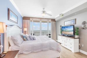 a bedroom with a white bed and a television at San Carlos 1503 in Gulf Shores