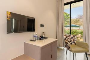 a room with a table and a chair and a television at Vanam at Sasan in Sasan Gir