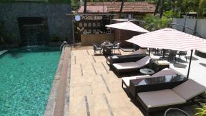 a swimming pool with chairs and umbrellas and a table and chairs at Kamah, Goa in Anjuna
