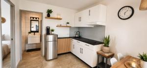 a kitchen with white cabinets and a stainless steel refrigerator at Island Vibes Apartment in Noord