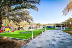 a park with a playground and a palm tree at Palm Escape Farmhouse - By Seven Elements in Ras al Khaimah
