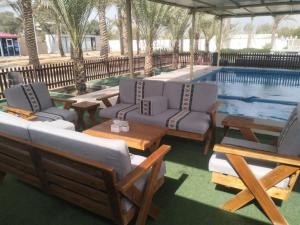 a pool with chairs and tables and a swimming pool at Palm Escape Farmhouse - By Seven Elements in Ras al Khaimah