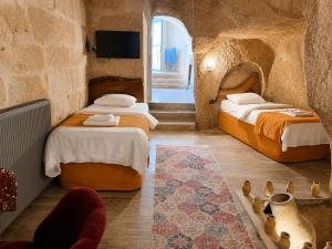 a bedroom with two beds and a tv in a room at Cappadocia Cave House in Ürgüp